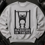 Grey sweatshirt with a graphic of a frog on a pull-up bar and text "HANGING IN THERE".