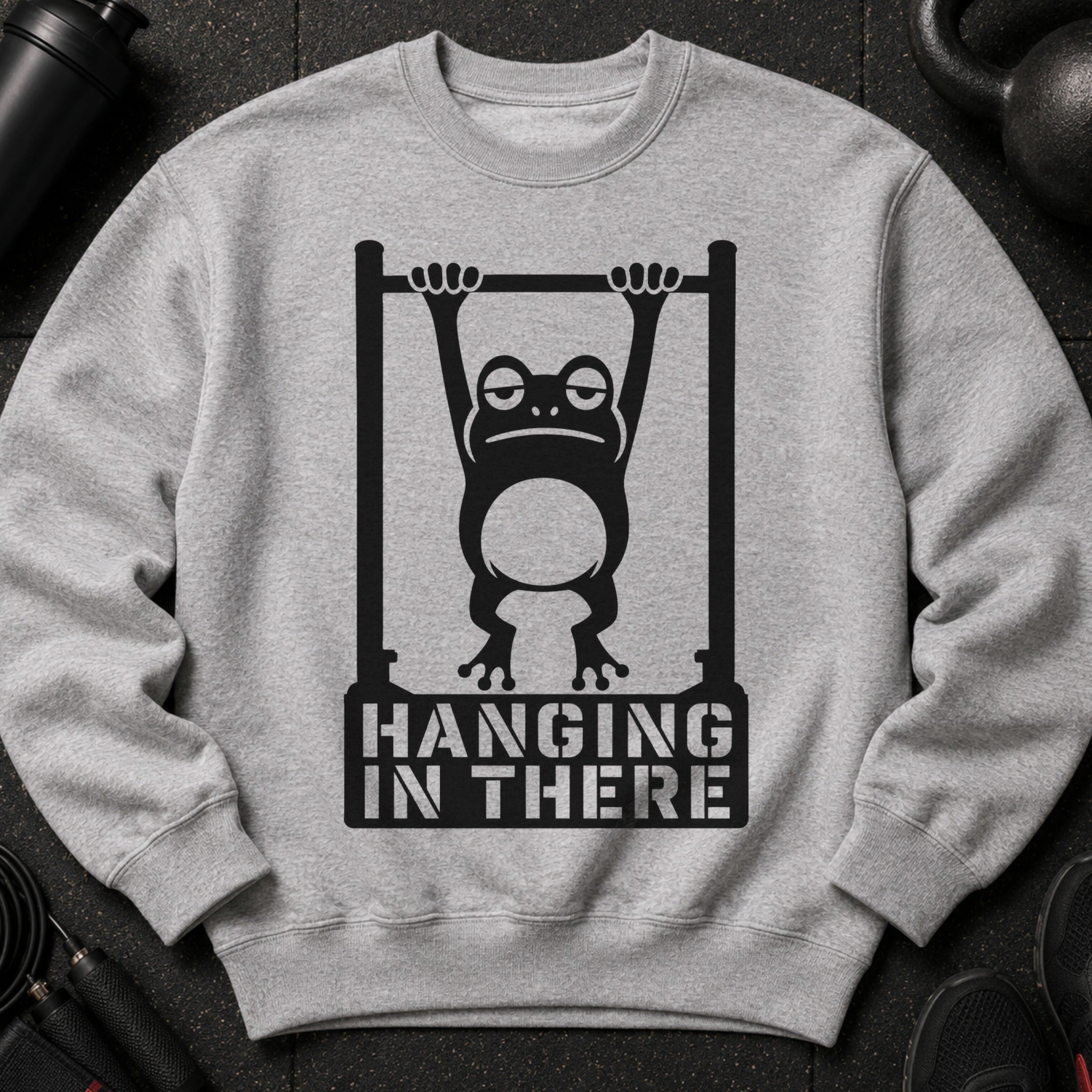Grey sweatshirt with a graphic of a frog on a pull-up bar and text "HANGING IN THERE".