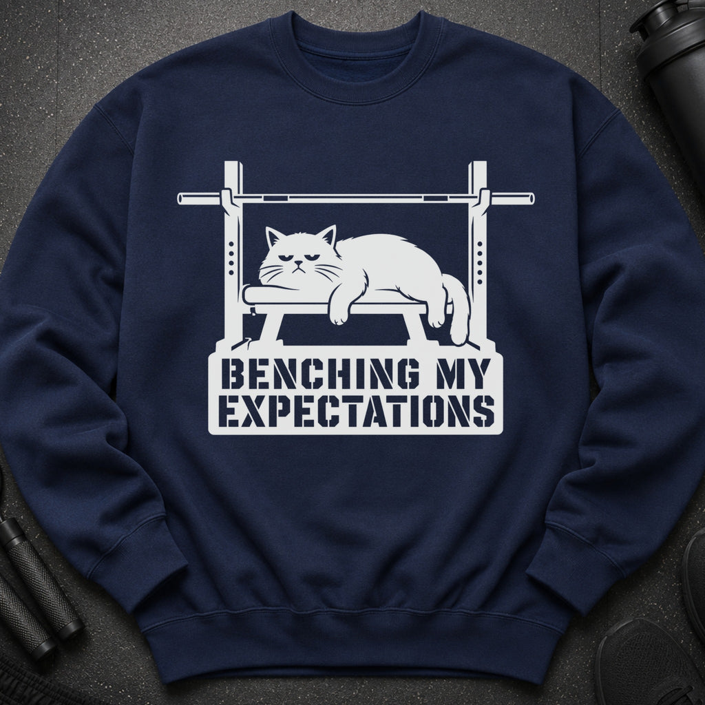 Navy sweatshirt with white graphic of a cat on a bench press reading "Benching My Expectations."
