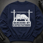 Navy sweatshirt with white graphic of a cat on a bench press reading "Benching My Expectations."