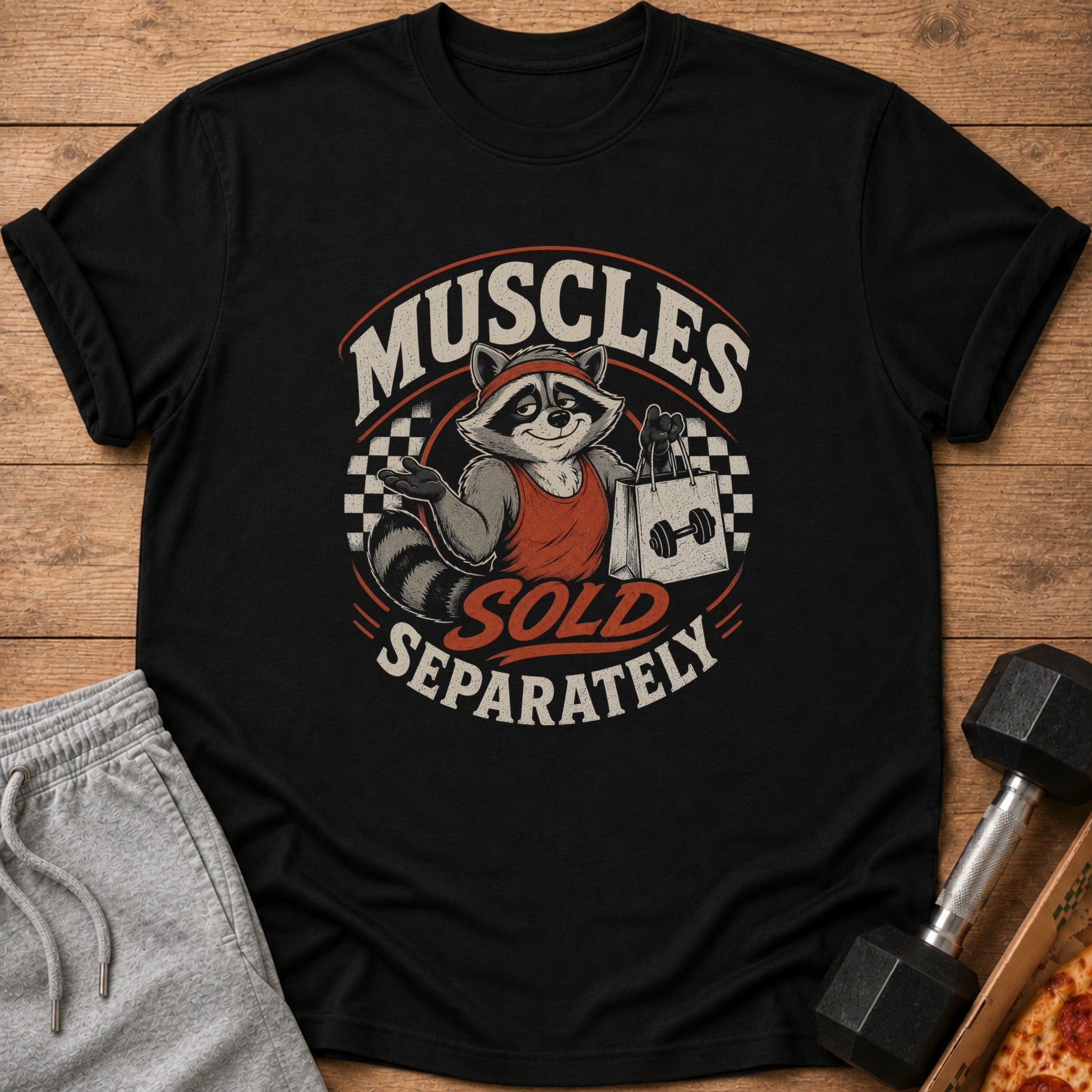 Black t-shirt with a raccoon graphic and text "Muscles Sold Separately".