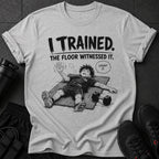 Graphic tee with "I TRAINED. THE FLOOR WITNESSED IT." and exhausted anime character.