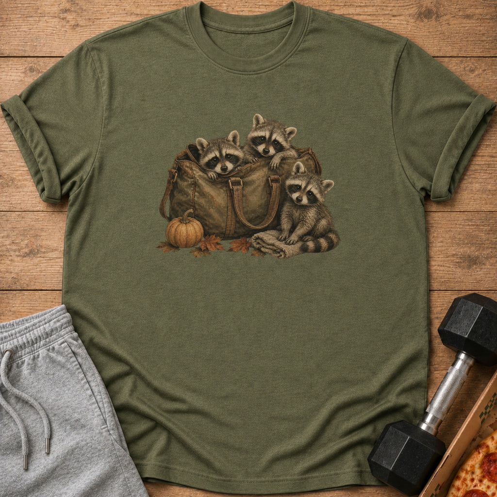 T-shirt graphic of three raccoons peeking out of a duffel bag with a pumpkin.