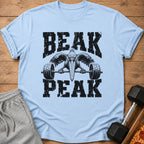 Light blue t-shirt with distressed black text "BEAK PEAK" and a pelican lifting a barbell.