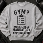 Grey sweatshirt with "GYM? MORE LIKE A MANDATORY APPOINTMENT" text and checklist graphic.