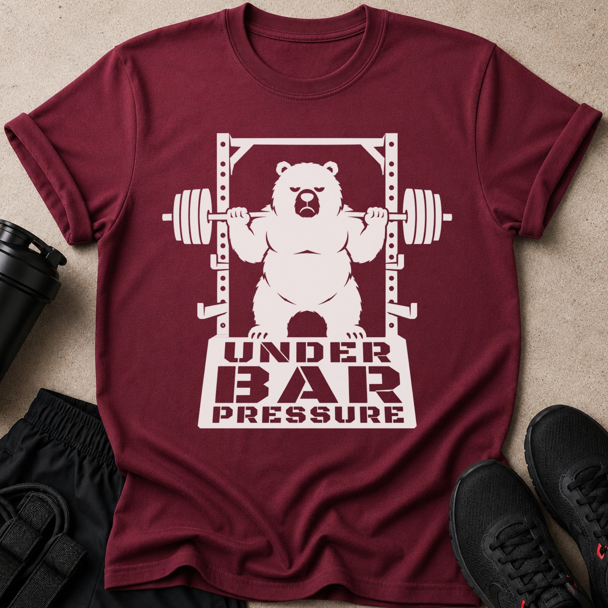 Maroon t-shirt with a white graphic of a bear lifting a barbell and text "UNDER BAR PRESSURE".
