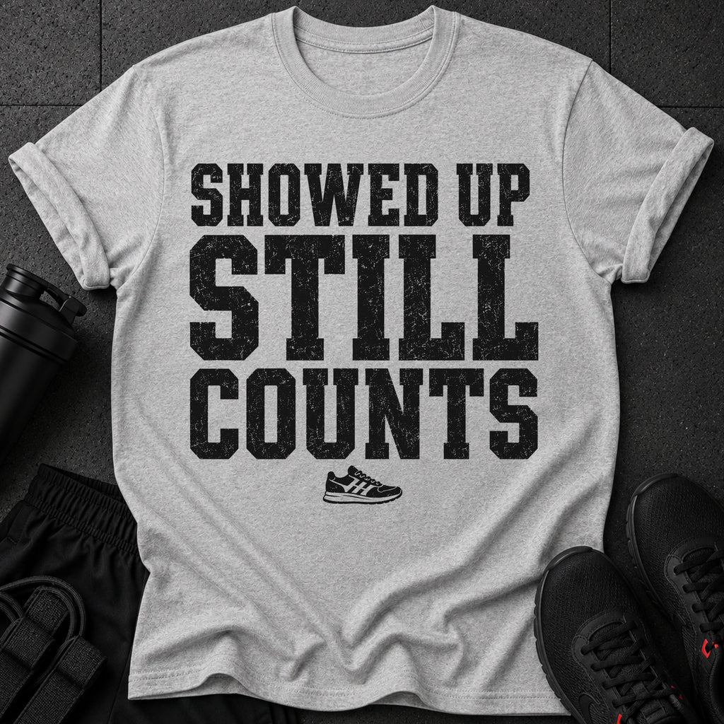 Gray t-shirt with distressed black text: "SHOWED UP STILL COUNTS" and a small sneaker graphic.