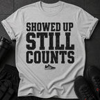 Gray t-shirt with distressed black text: "SHOWED UP STILL COUNTS" and a small sneaker graphic.