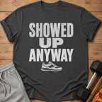 Dark gray t-shirt with white text "SHOWED UP ANYWAY" and a running shoe graphic.