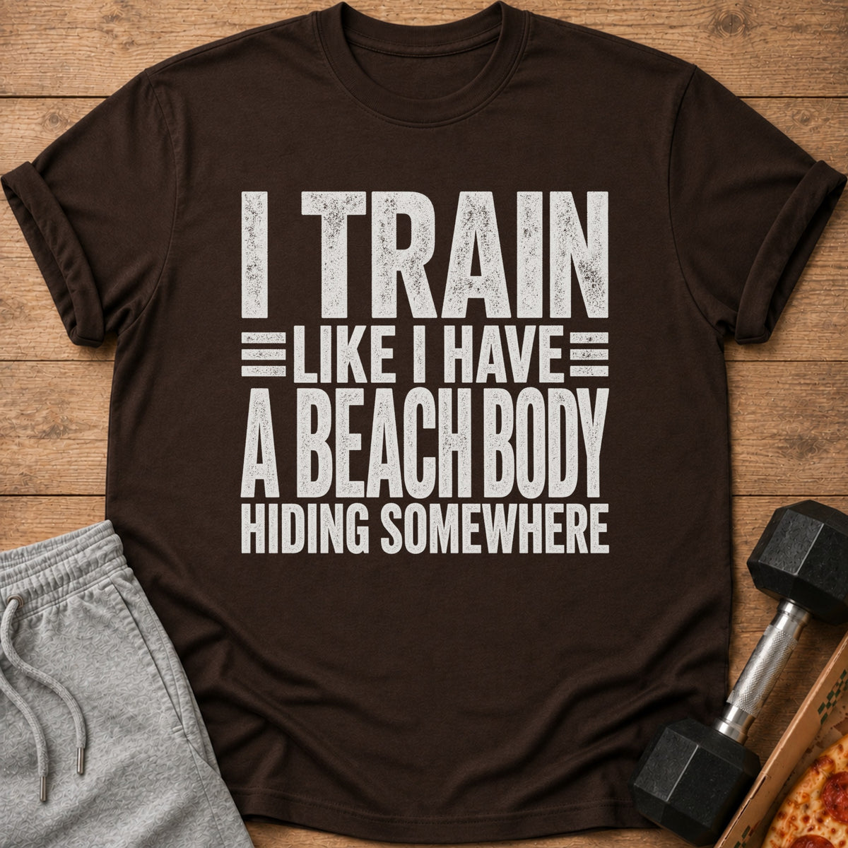 Brown t-shirt with white text: "I TRAIN LIKE I HAVE A BEACH BODY HIDING SOMEWHERE".