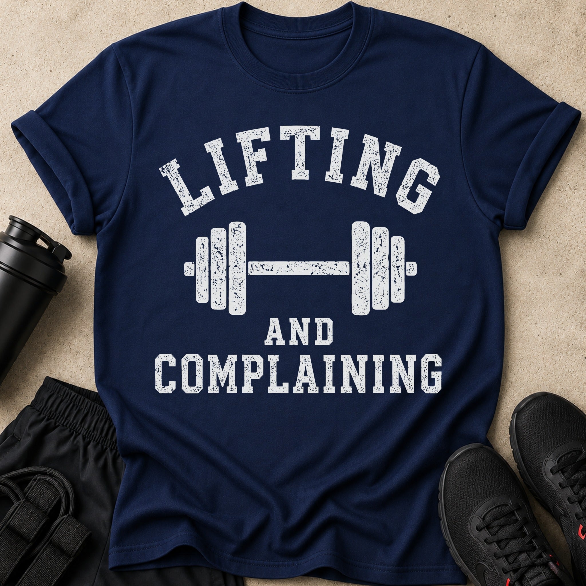 Navy t-shirt with white distressed text "Lifting and Complaining" and barbell graphic.