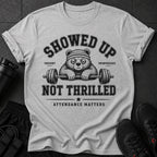 Grey t-shirt with a bear wearing a headband, holding a barbell, and text "SHOWED UP UNIMPRESSED" and "NOT THRILLED".