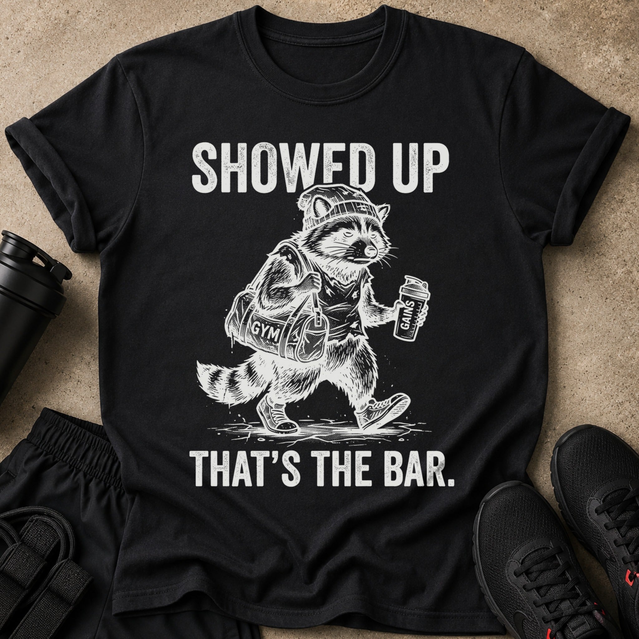 Black t-shirt with raccoon gym graphic and text "SHOWED UP THAT'S THE BAR."