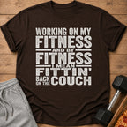Brown t-shirt with white text reading "Working on my fitness and by fitness I mean fittin' back on the couch".