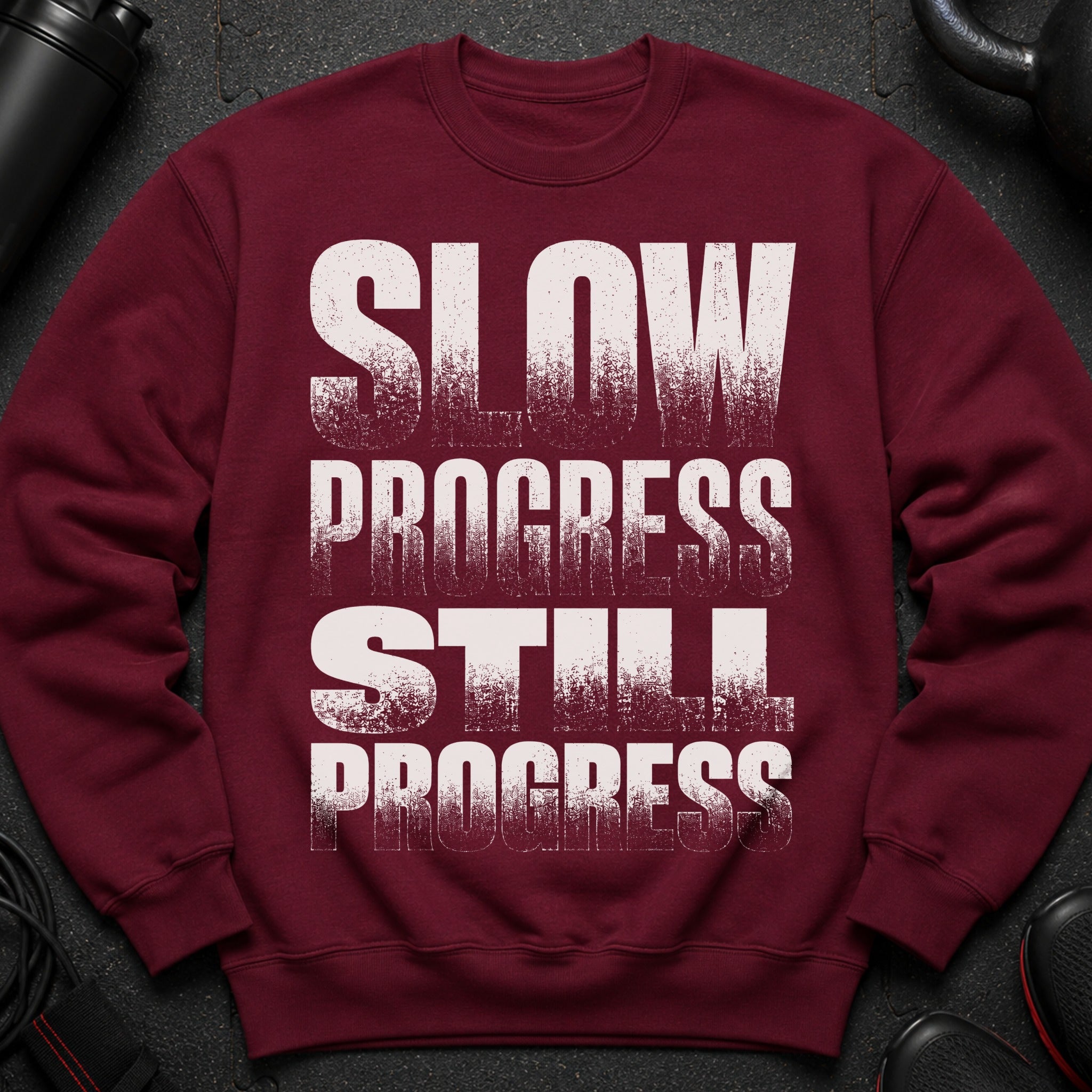 Maroon sweatshirt with white text "SLOW PROGRESS STILL PROGRESS".