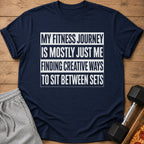 Navy t-shirt with white text "My fitness journey is mostly just me finding creative ways to sit between sets".
