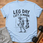 Light blue t-shirt with "LEG DAY LEFT A MARK" text and a skeleton at the gym.