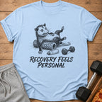 Opossum lying on a foam roller with a dumbbell and water bottle, text reads "Recovery Feels Personal".