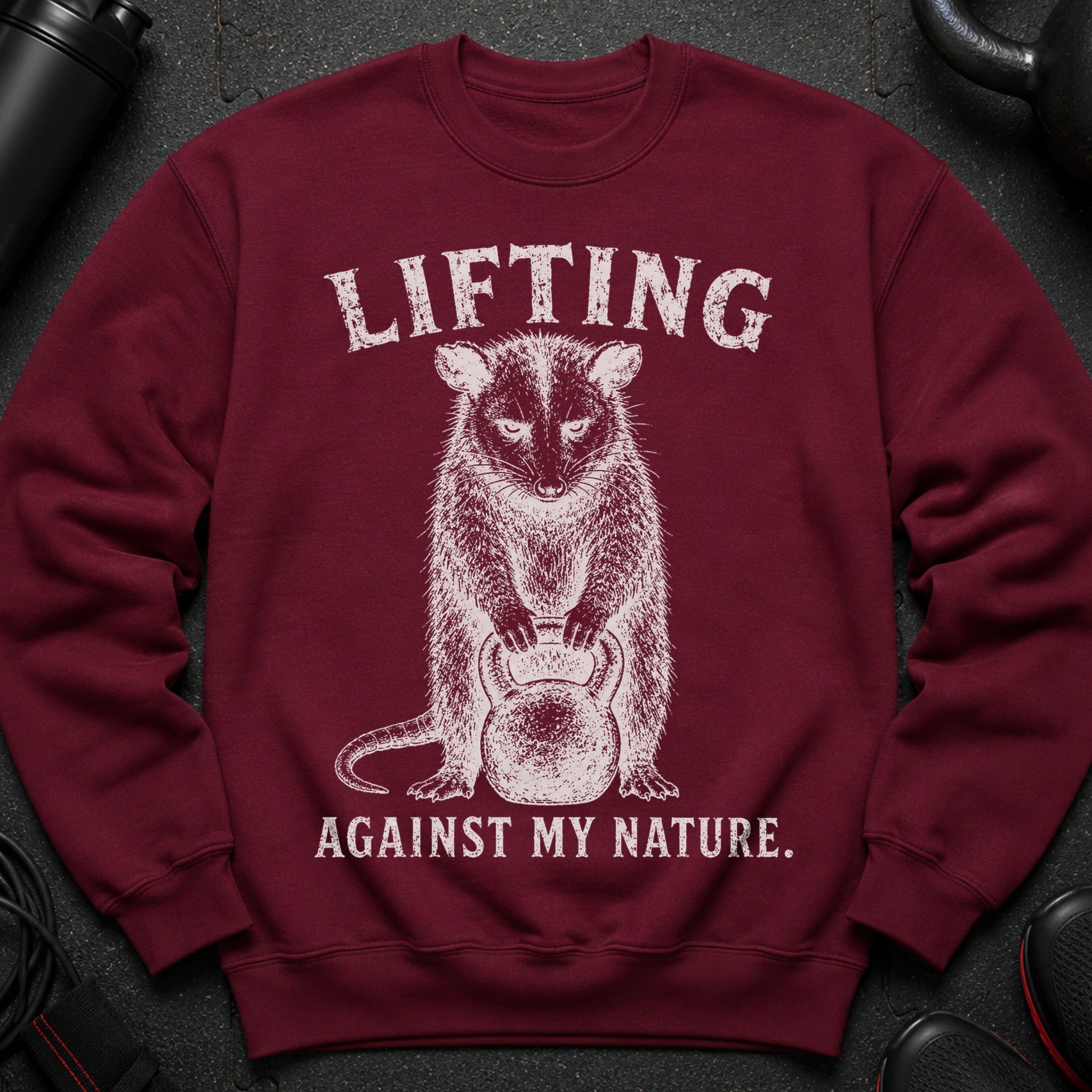 Maroon sweatshirt with distressed white graphic of an animal holding a kettlebell and text.