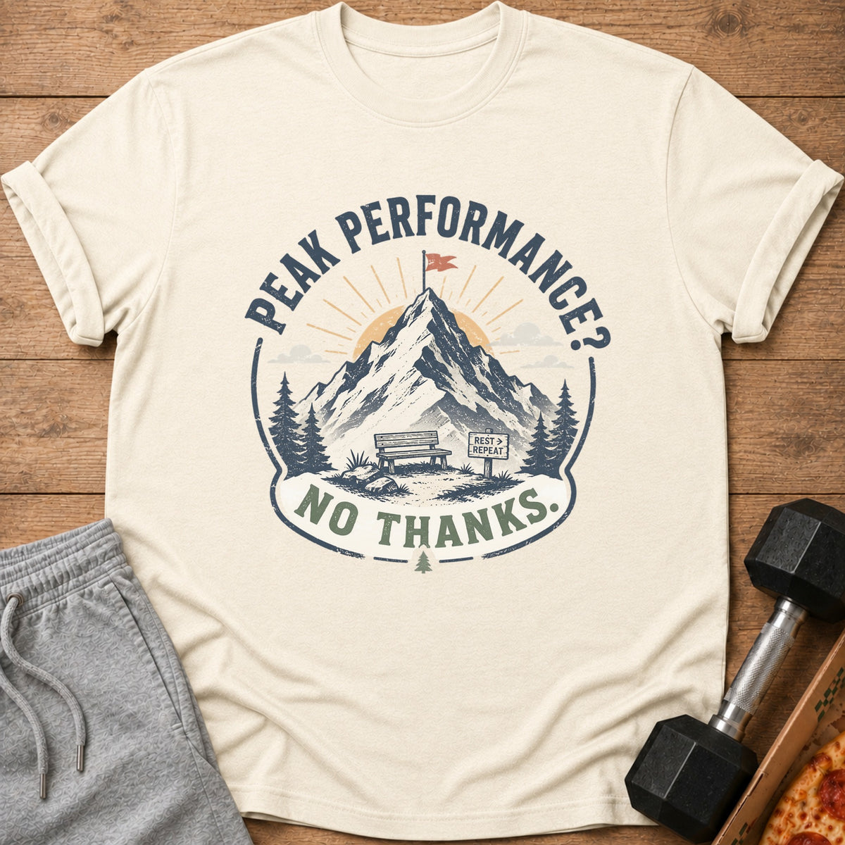 Cream t-shirt with "Peak Performance? No Thanks." mountain graphic and a "Rest > Repeat" sign.