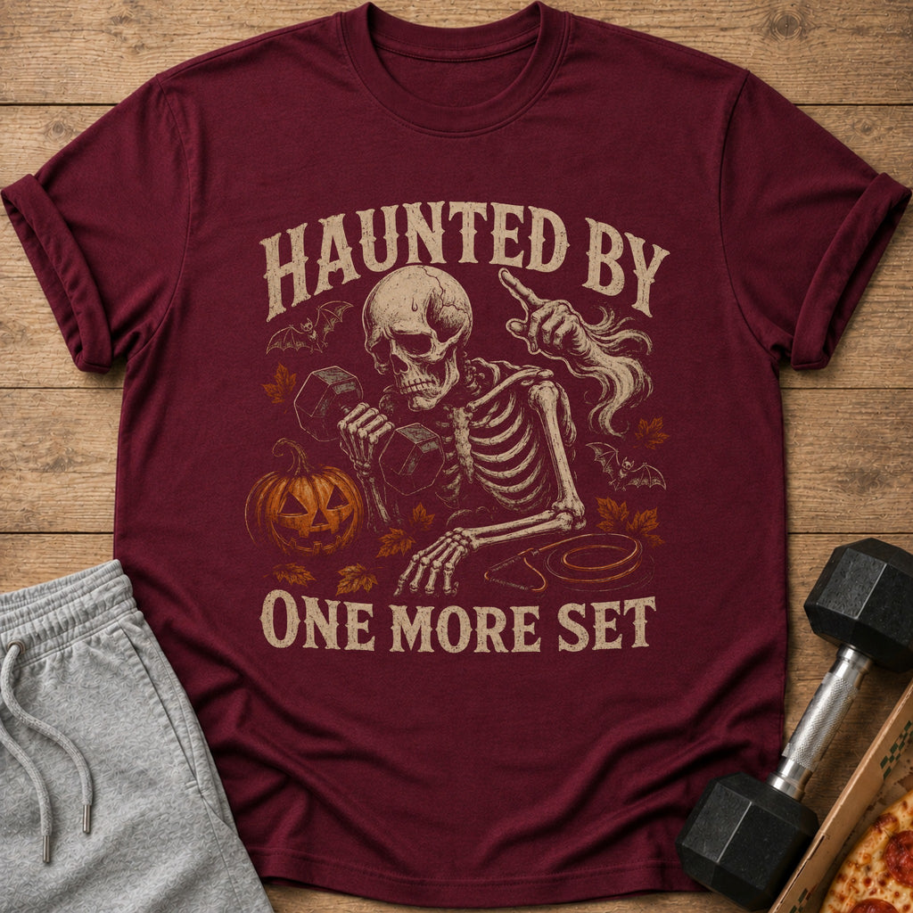 Maroon t-shirt with skeleton lifting weights and text "Haunted by One More Set".