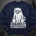 Navy sweatshirt with a white graphic of a raccoon holding two kettlebells and the text "RARELY MOTIVATED".