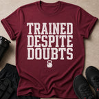 Maroon t-shirt with distressed white text "TRAINED DESPITE DOUBTS" and a kettlebell icon.