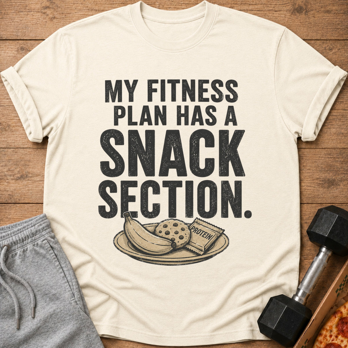 Cream t-shirt with "My Fitness Plan Has A Snack Section" text and snack illustration.
