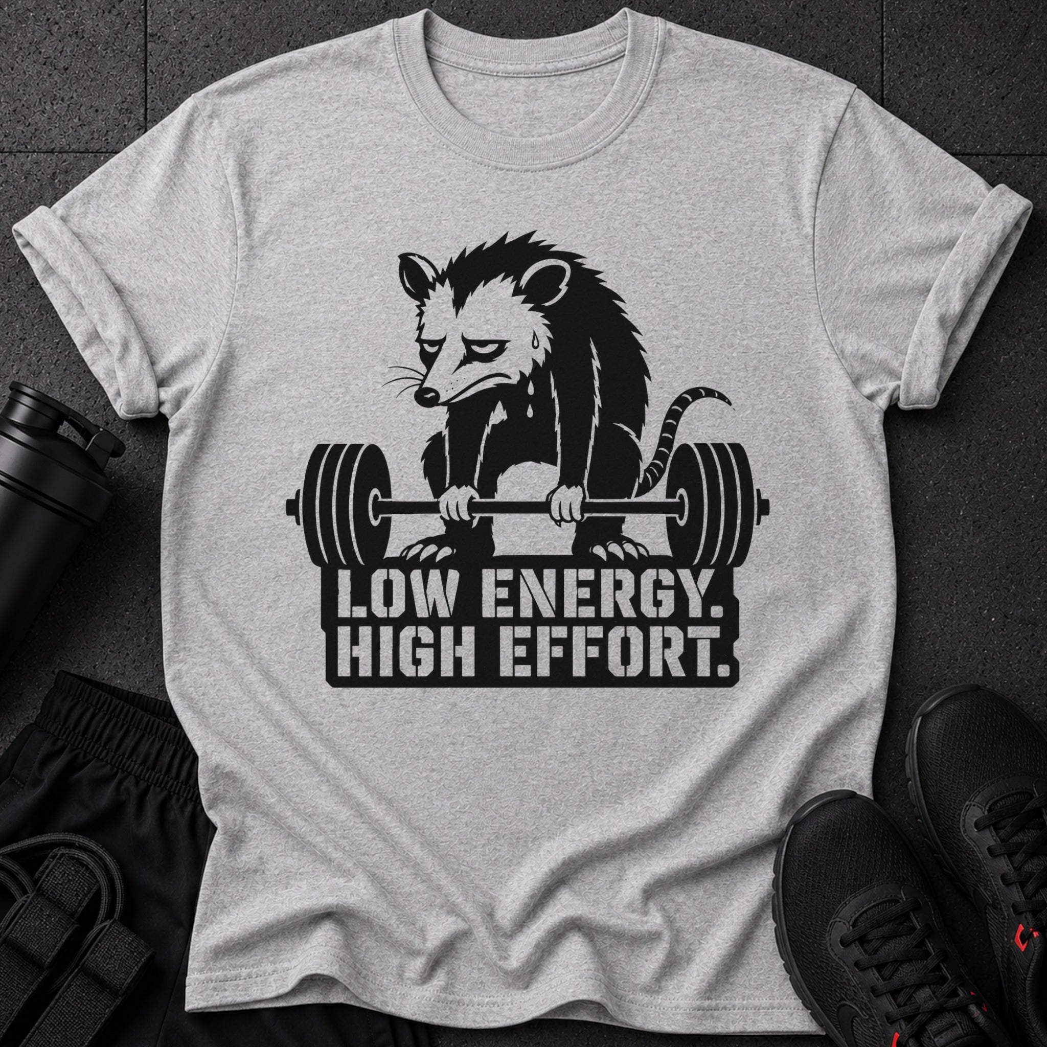 Light gray t-shirt with a black graphic of a possum lifting weights and text.