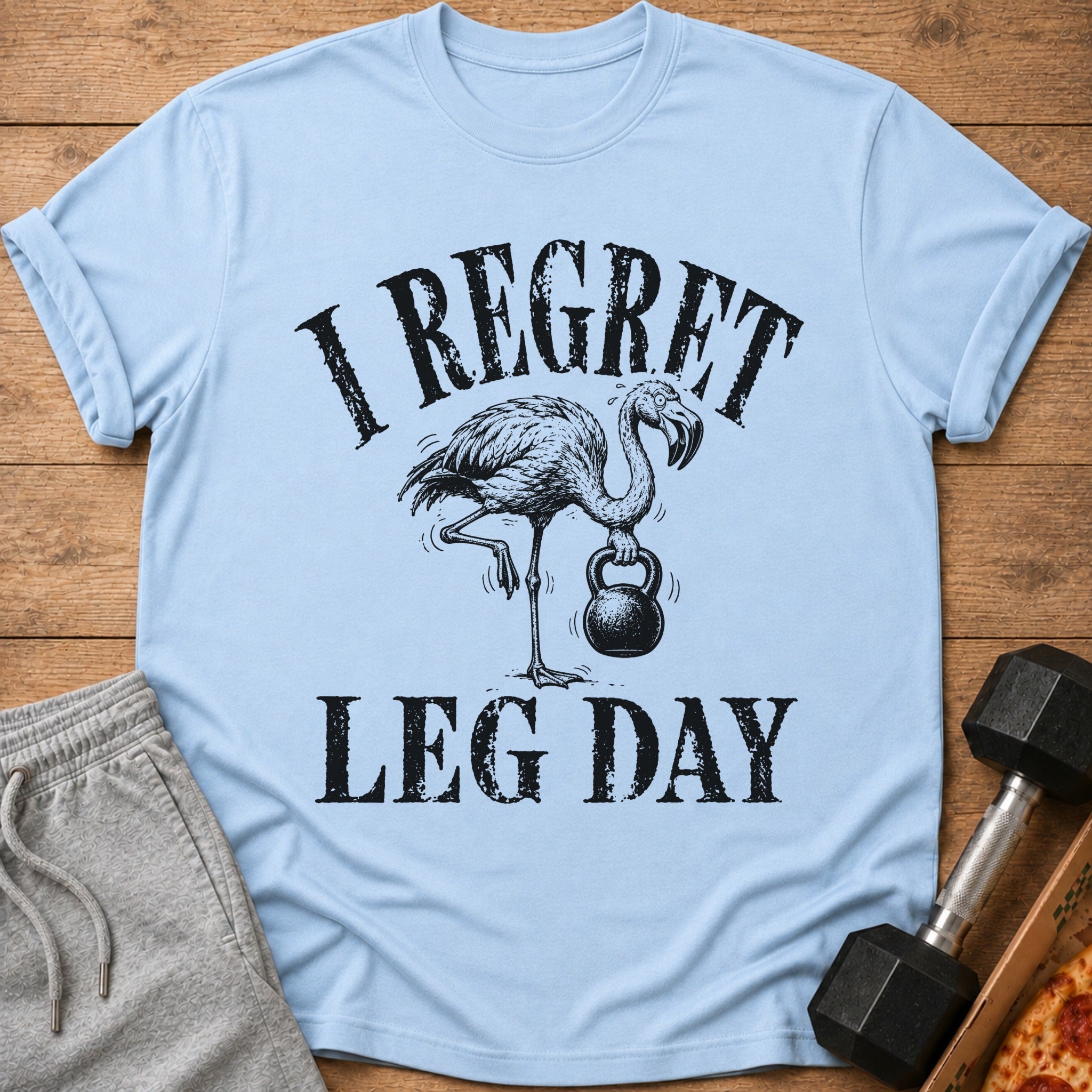Light blue t-shirt with flamingo holding kettlebell and text "I REGRET LEG DAY".