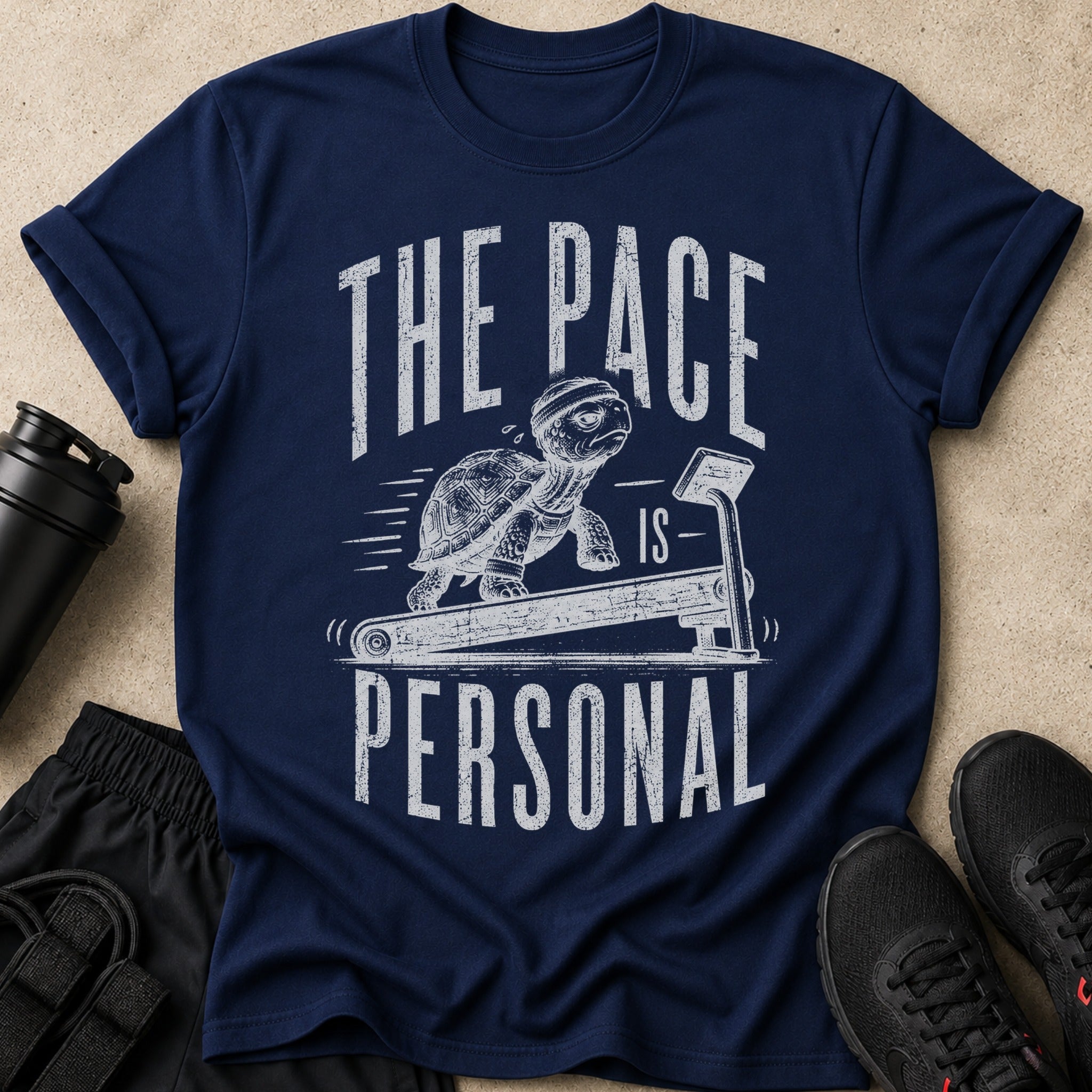 Navy t-shirt with a tortoise running on a treadmill and text "THE PACE IS PERSONAL".