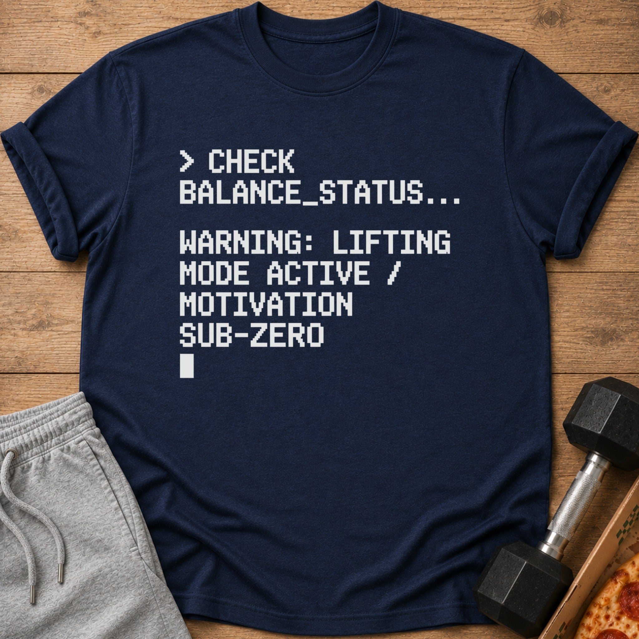 Navy t-shirt with white pixelated text: "> CHECK BALANCE_STATUS... WARNING: LIFTING MODE ACTIVE / MOTIVATION SUB-ZERO"