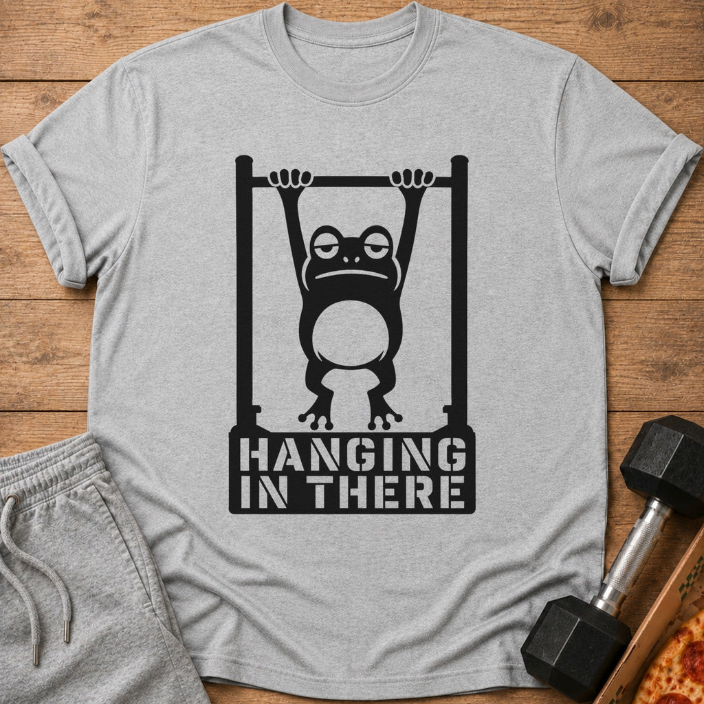 Grey t-shirt with black graphic of a tired frog hanging from a pull-up bar and text "HANGING IN THERE".
