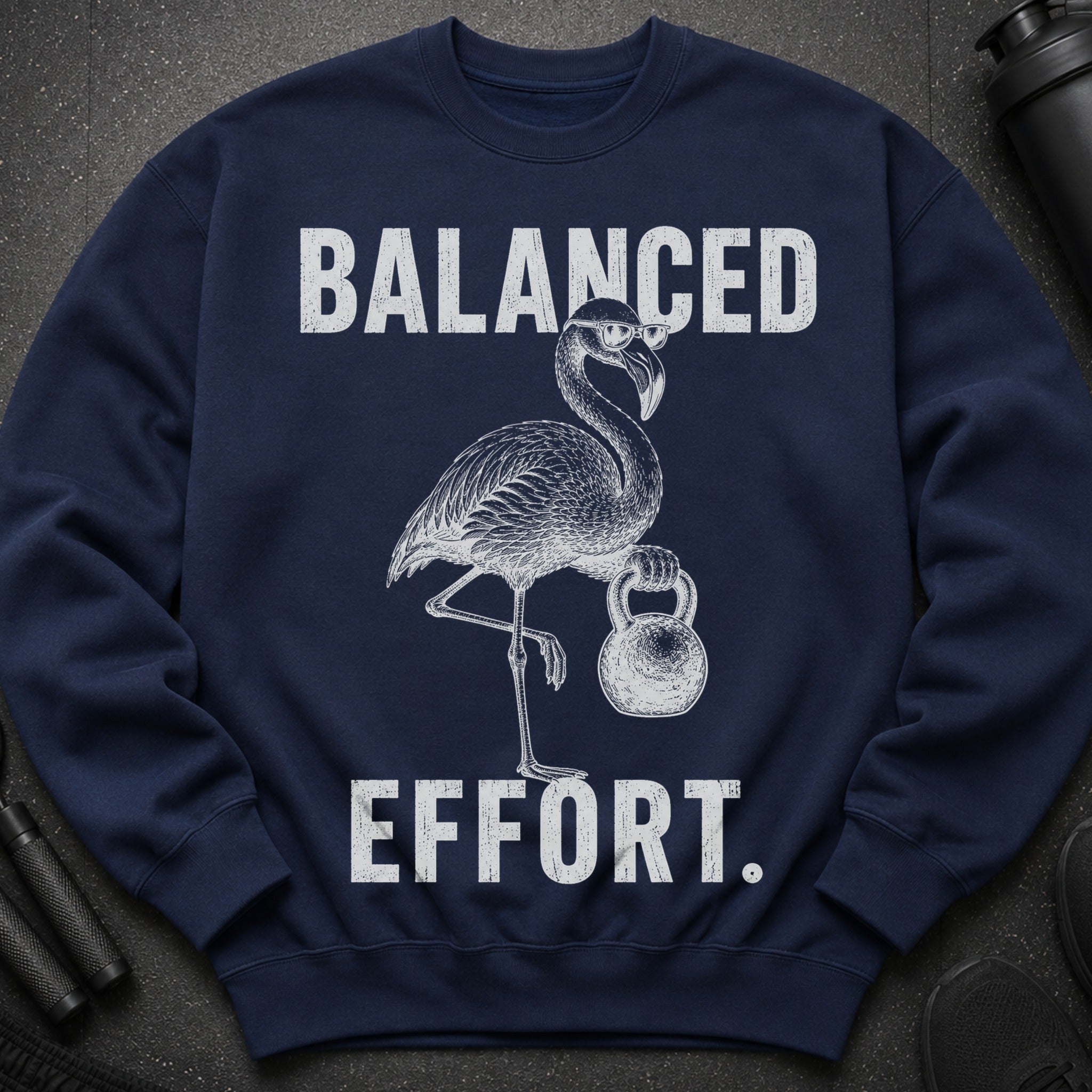 Navy sweatshirt with a drawing of a flamingo lifting a kettlebell. Text says "BALANCED EFFORT."