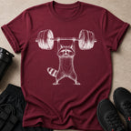 Maroon t-shirt with white sketch of raccoon weightlifting barbell.