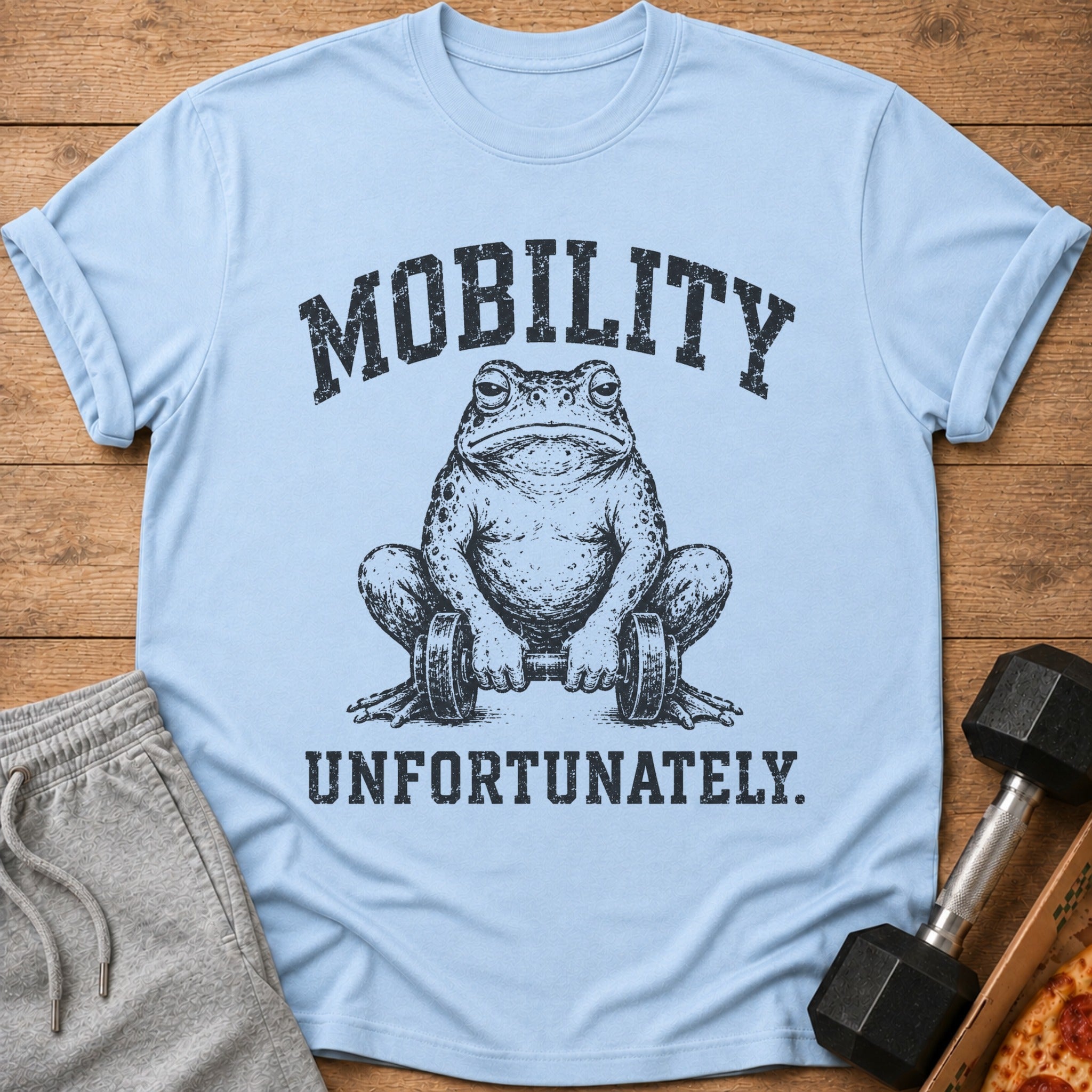 Light blue t-shirt with a distressed graphic of a frog holding dumbbells and the text "MOBILITY UNFORTUNATELY."
