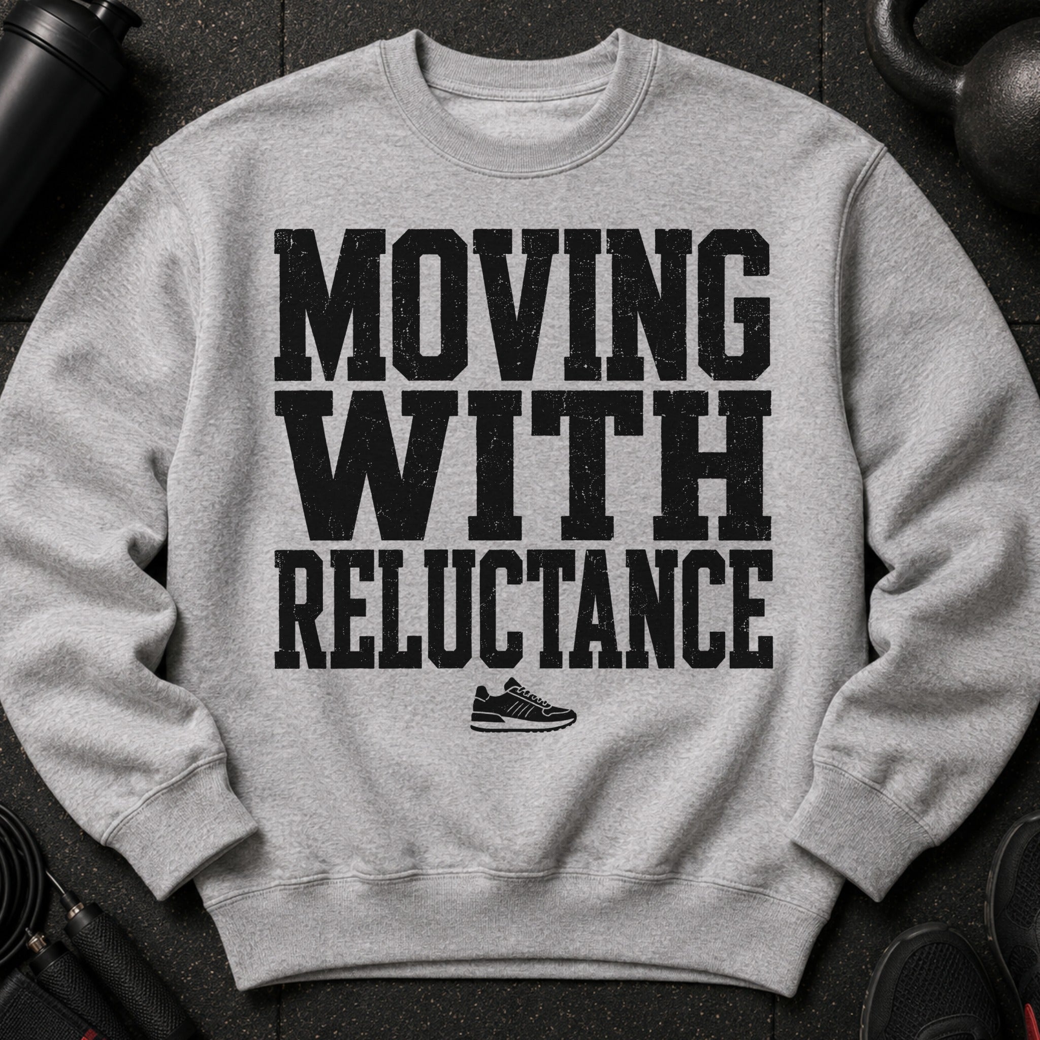 Grey crewneck sweatshirt with black text "MOVING WITH RELUCTANCE" and a sneaker graphic.