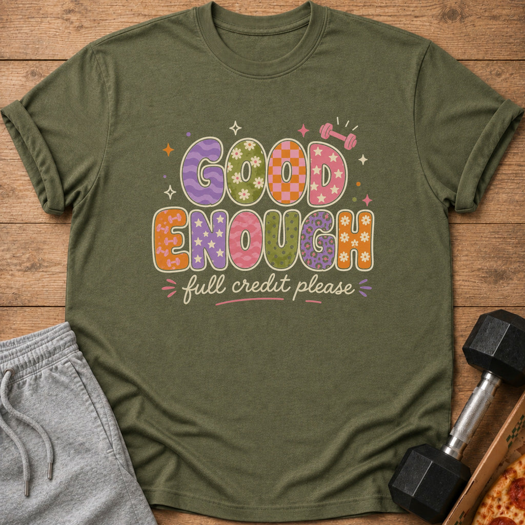 Olive green t-shirt with "GOOD ENOUGH full credit please" text and playful graphics.