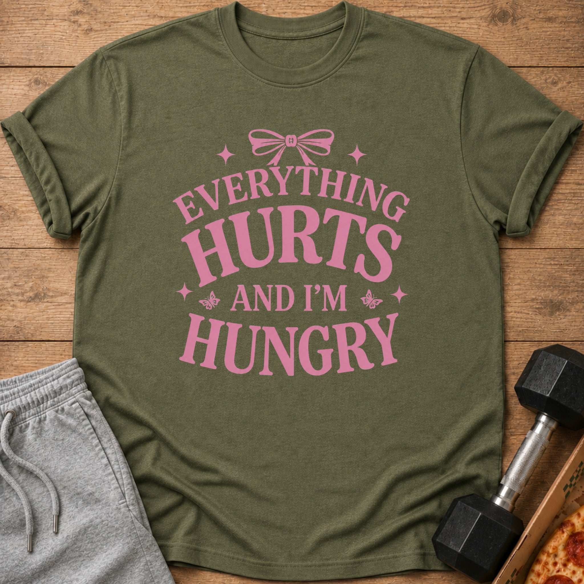 Olive green t-shirt with pink text that reads "Everything Hurts And I'm Hungry".