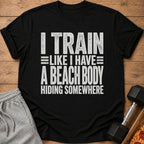Black t-shirt with white text: "I TRAIN LIKE I HAVE A BEACH BODY HIDING SOMEWHERE".