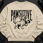 Crewneck sweatshirt with black graphic of dog lifting dumbbell and text "PAWSITIVE".