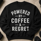 Black sweatshirt with white distressed text "POWERED BY COFFEE & REGRET".