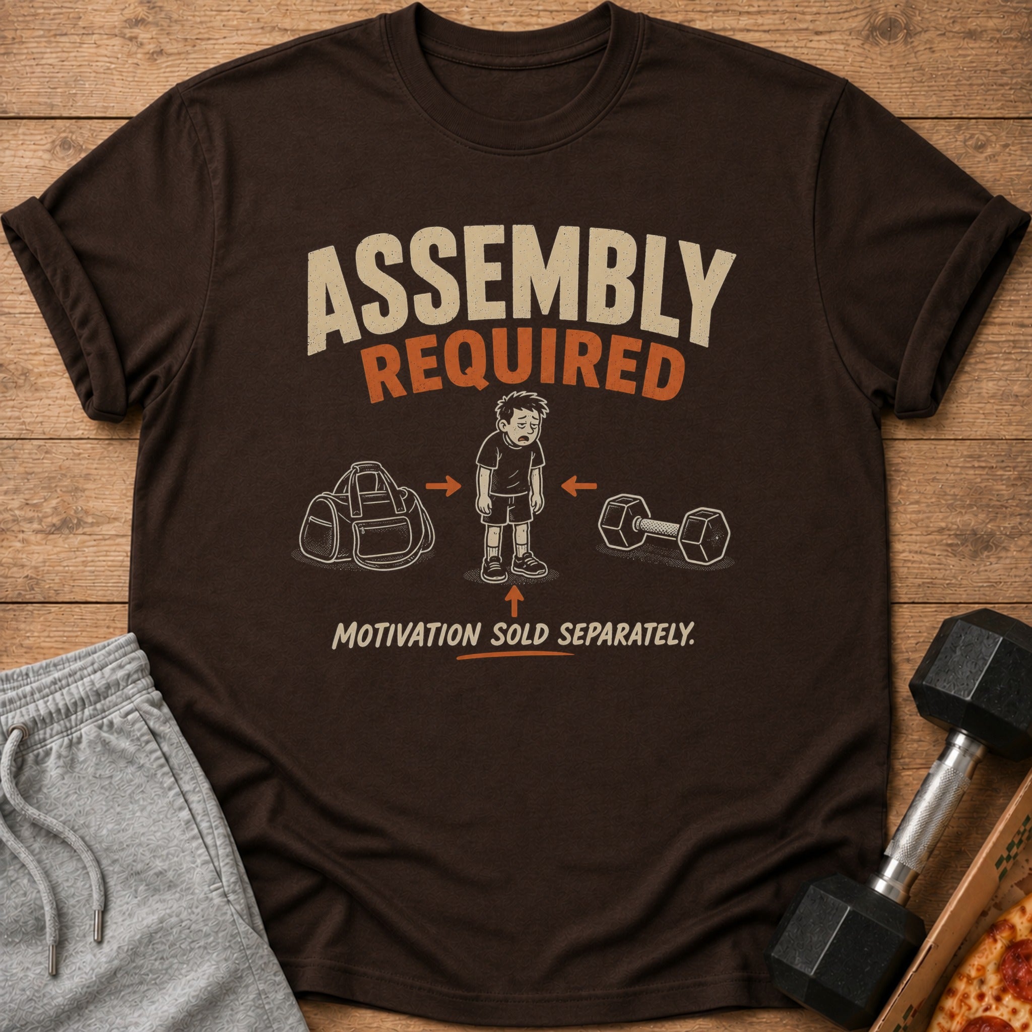 T-shirt with "Assembly Required" and cartoon of unmotivated boy between gym bag and dumbbell.