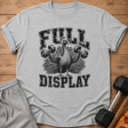 A heather grey t-shirt features a black graphic of a peacock lifting dumbbells with the text FULL DISPLAY.