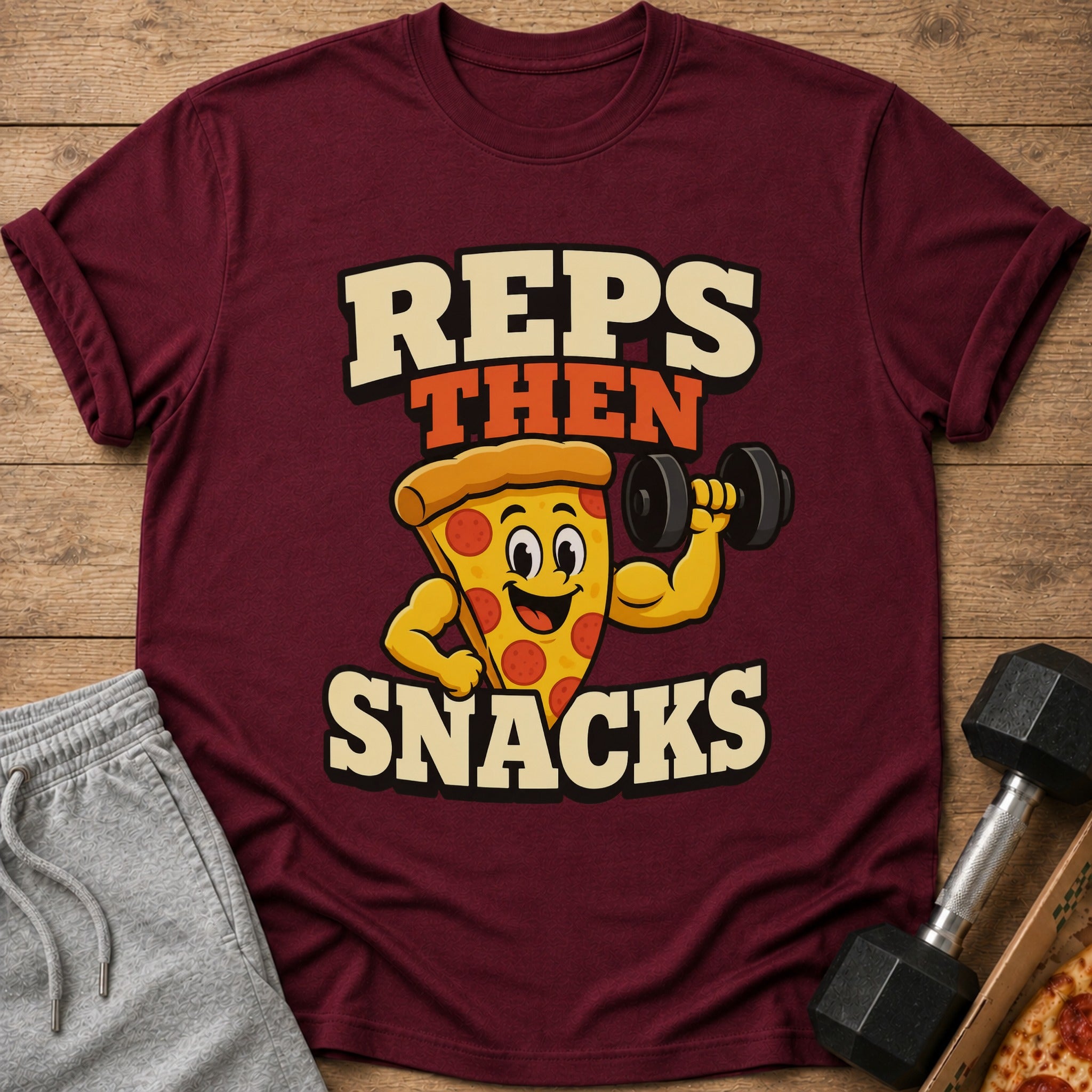 Maroon t-shirt with cartoon pizza lifting dumbbell and text "REPS THEN SNACKS".