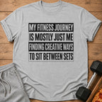 Grey t-shirt with text "My fitness journey is mostly just me finding creative ways to sit between sets."