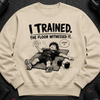Light tan sweatshirt with black text "I TRAINED. THE FLOOR WITNESSED IT." and cartoon of exhausted person.