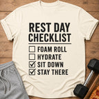 Cream t-shirt with black text: "REST DAY CHECKLIST FOAM ROLL HYDRATE SIT DOWN STAY THERE"