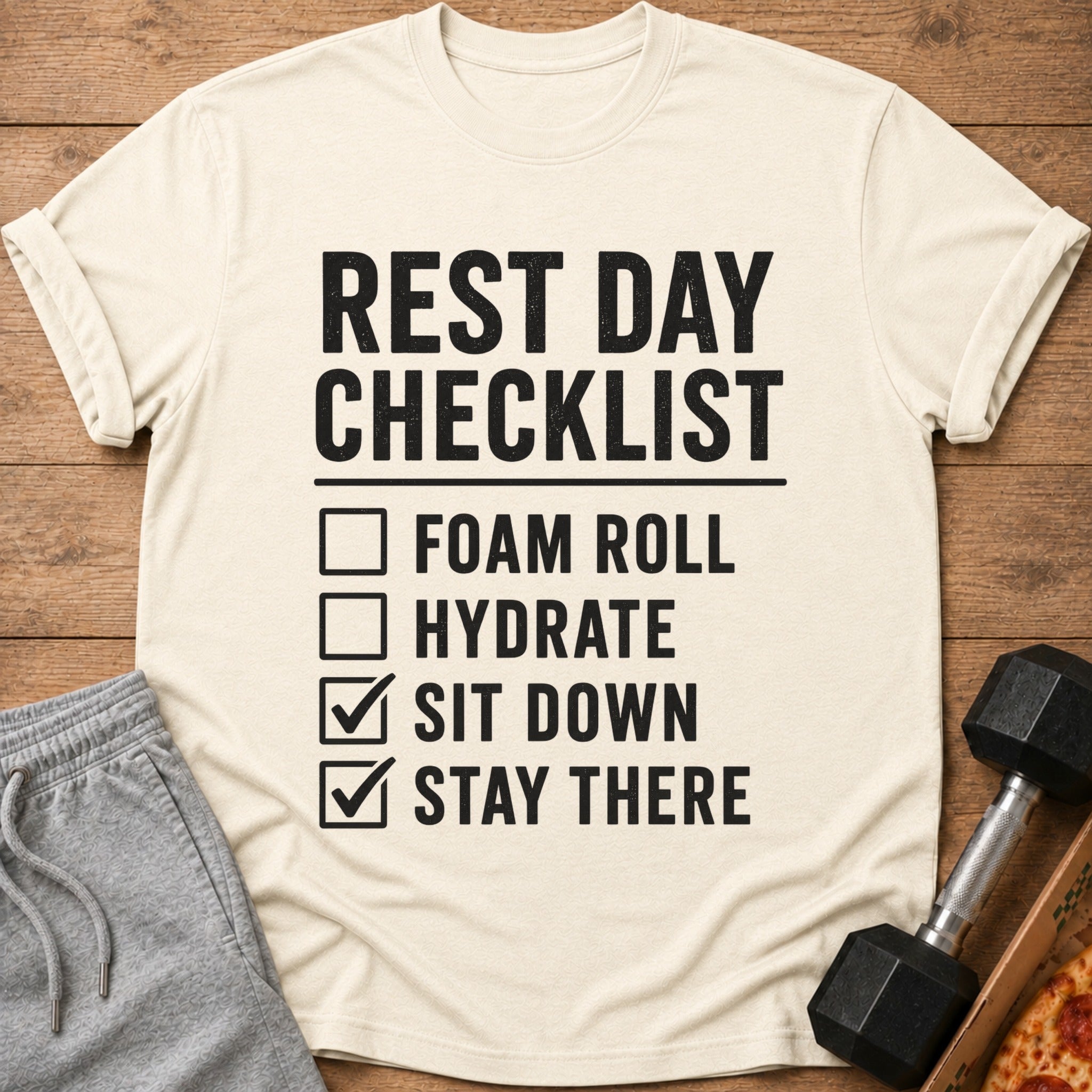 Cream t-shirt with black text: "REST DAY CHECKLIST FOAM ROLL HYDRATE SIT DOWN STAY THERE"