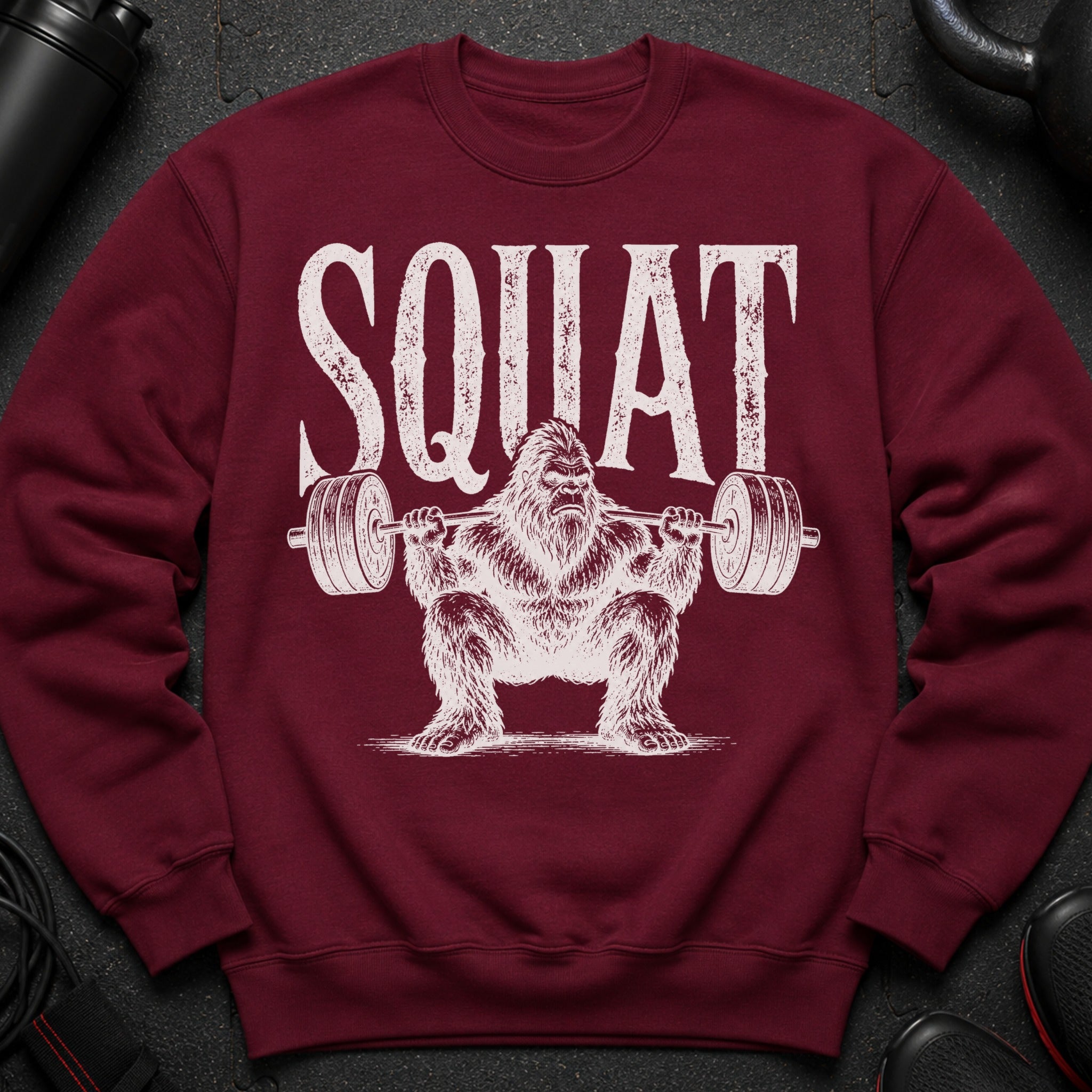 Maroon sweatshirt with distressed white "SQUAT" text and Bigfoot lifting weights graphic.